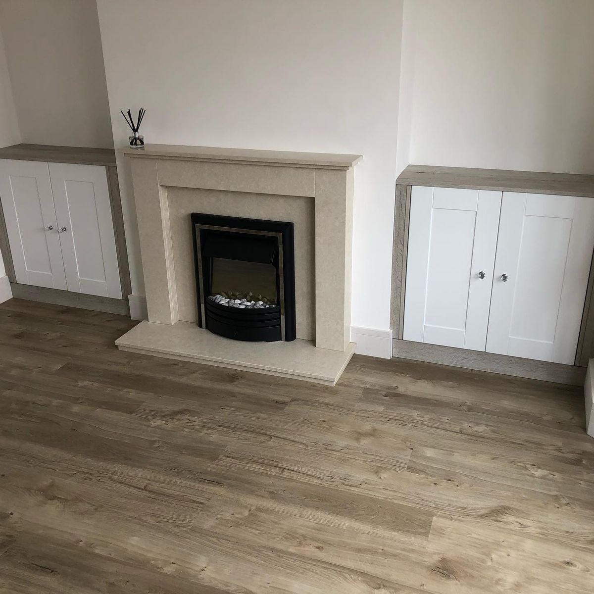 White alcove units either side of a fireplace, with a new Amtico floor