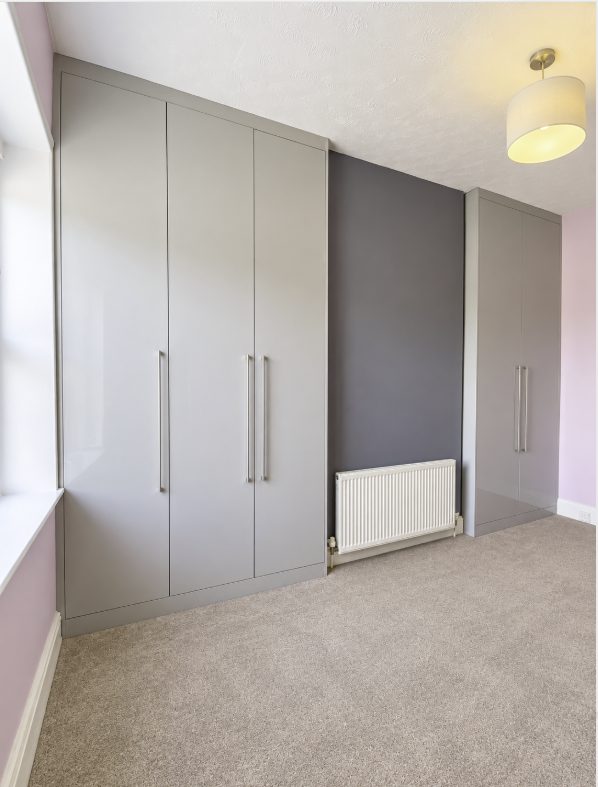 Stone grey fitted wardrobes running floor to ceiling across a bedroom